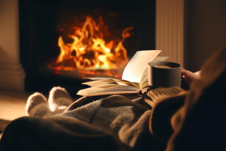 person reading in front of fireplace