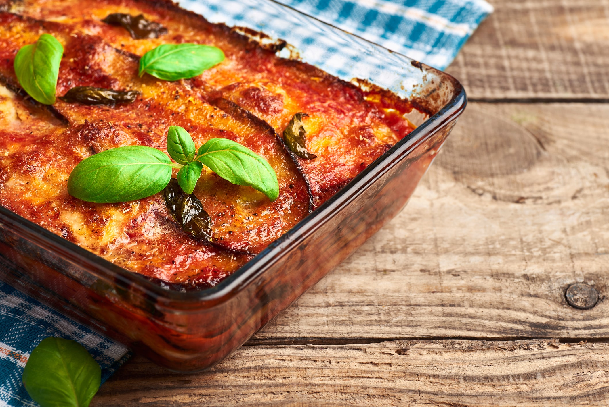 Italian traditional eggplant parmigiana pie with fresh basil and mozzarella cheese. Homemade eggplant parmigiana.
